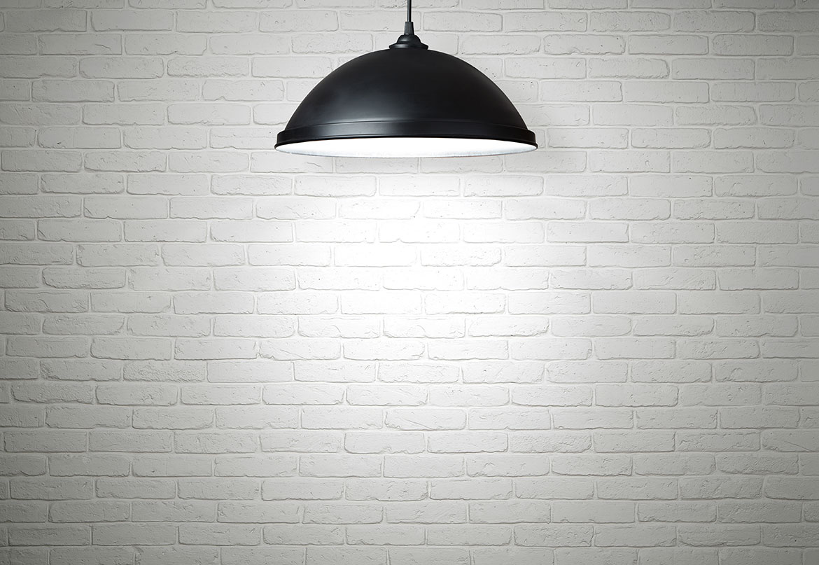 black drop lamp in front of a white brick wall
