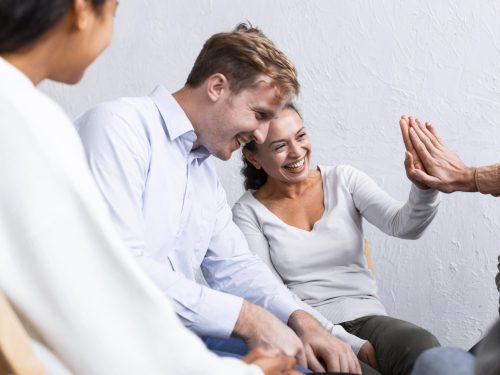 smiley-people-group-therapy-session-high-fiving-each-other group of individuals smiling and high high fiving