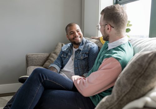 Happy gay couple image, sitting on a couch at home