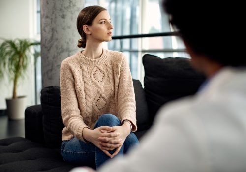Young woman looking away while having a meeting with psychotherapist at the clinic.